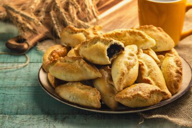 Yeşil ahşap masada haşhaş tohumlu taze çörek sergisi. Ev yapımı çörek..