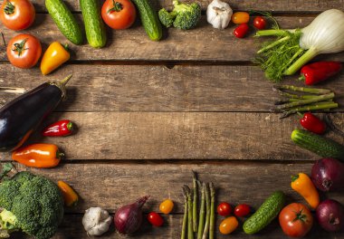 Tahta masada taze organik sebzeler sergileniyor. Domates, biber, brokoli, soğan, sarımsak, salatalık, patlıcan, siyah göz bezelyesi, ekolojik çanta..