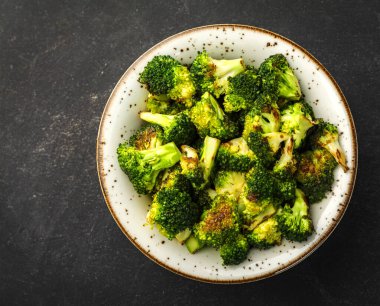 Siyah tabakta pişmiş sebzeler ve koyu arkaplan, fırında soğan, brokoli, sarımsak, kırmızı ve sarı biber, mantar..