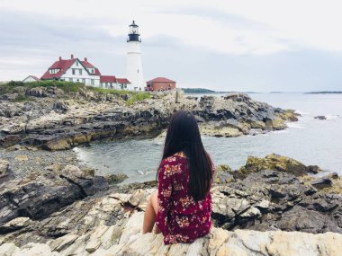 Woman enjoying beautiful view of Portland lighthouse in Portland Maine USA clipart
