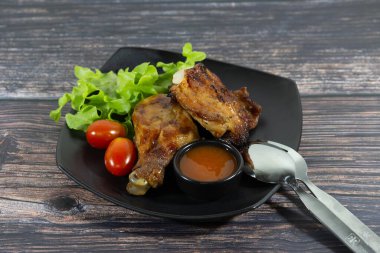Ahşap tahtada ızgara tavuk, sos ve domates.