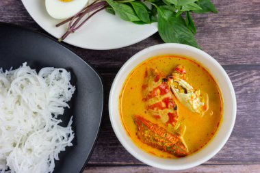 Sebzeli köri soslu Tayland pilavı ve ahşap masada haşlanmış yumurta. Erişte gibi yuvarlak undan yapılmış Tayland yemeği stili, acı biber ezmesiyle yenir..