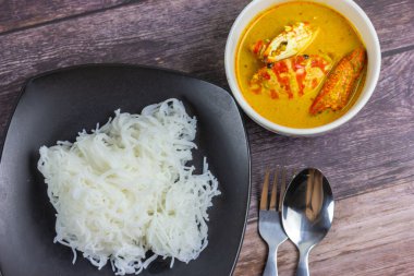 Sebzeli köri soslu Tayland pilavı ve ahşap masada haşlanmış yumurta. Erişte gibi yuvarlak undan yapılmış Tayland yemeği stili, acı biber ezmesiyle yenir..