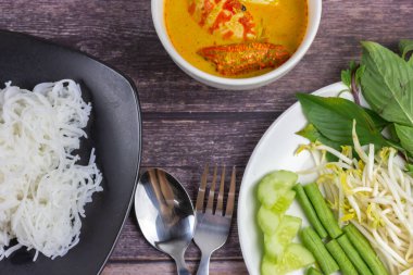 Sebzeli köri soslu Tayland pilavı ve ahşap masada haşlanmış yumurta. Erişte gibi yuvarlak undan yapılmış Tayland yemeği stili, acı biber ezmesiyle yenir..