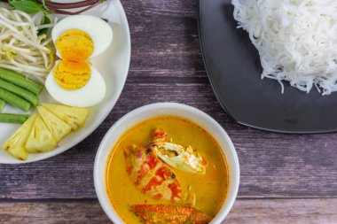 Sebzeli köri soslu Tayland pilavı ve ahşap masada haşlanmış yumurta. Erişte gibi yuvarlak undan yapılmış Tayland yemeği stili, acı biber ezmesiyle yenir..