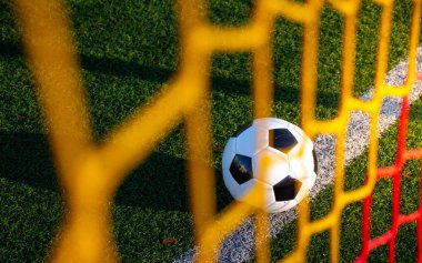 Renkli gol ağlarının arkasından vuruldu. Gol çizgisinde yatan bir futbol topu..