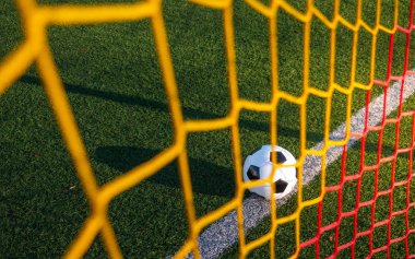 Renkli gol ağlarının arkasından vuruldu. Gol çizgisinde yatan bir futbol topu..