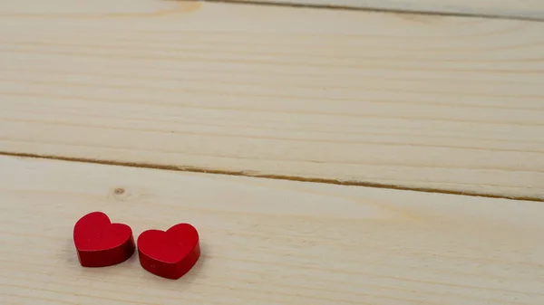 Due cuori rossi sdraiati su un tavolo di legno . — Foto Stock