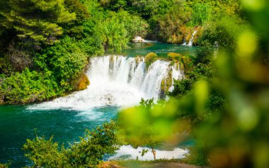 Yeşil ağaçlar ve çalılar arasında büyük bir şelale.