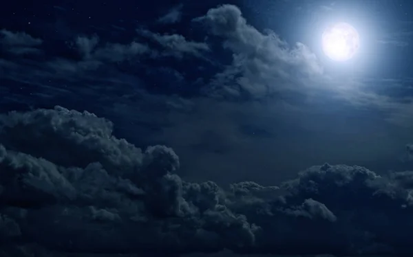 Gece gökyüzünde bulutlar arasında dolunay