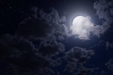 Gece gökyüzünde bulutlar arasında dolunay