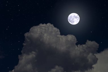 Gece gökyüzünde bulutlar arasında dolunay