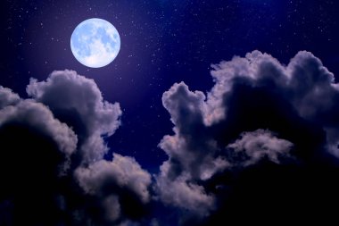 Gece gökyüzünde bulutlar arasında dolunay