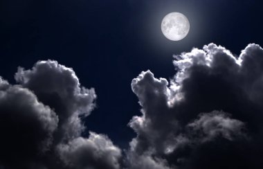 Gece gökyüzünde bulutlar arasında dolunay