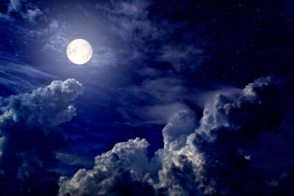 The full moon between the clouds in the night sky
