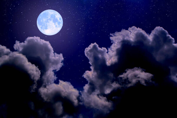 The full moon between the clouds in the night sky