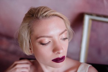 Kısa saçlı, inanılmaz güzel bir gelinin portresi. Kız kameraya farklı duygular gösteriyor..