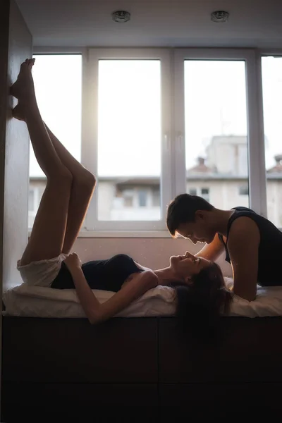 活動の概念 パートナーへの信頼 愛のカップルは ベッドの上に 自宅で抱擁にある 若い男がロフトの窓で女性とキスをする 恋人の手のタッチ — ストック写真