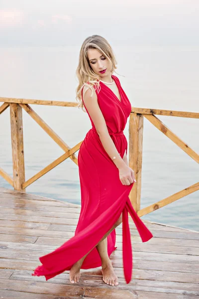 Urocza Dziewczyna Długiej Czerwonej Sukience Tańczy Pozuje Molo Tle Morza — Zdjęcie stockowe