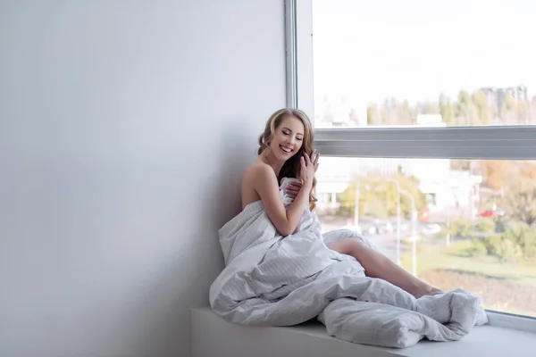 Uzun Saçlı Çekici Bir Kız Pencere Eşiğinde Bir Battaniyenin Içinde — Stok fotoğraf