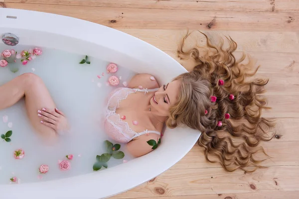 Sağlık ve güzellik. Banyoda uzun saçlı ve spa tedavisi gören bir kız. Saçlarında ve banyoda çiçekler var..