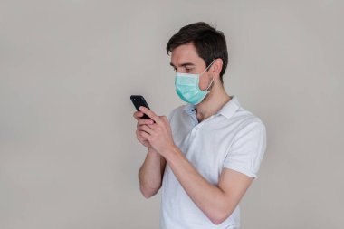 Uzaktan kumanda. Tıbbi maskeli adam bir dizüstü bilgisayar üzerinde çalışıyor ve telefonda konuşuyor. Tıbbi maskeli bir adam selfie çeker..
