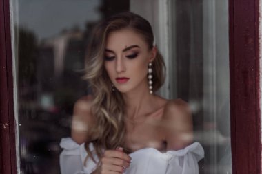 Gelinin Moda pozunun büyüleyici güzelliği pencerede. Pencereden modern bir gelinin portresi.