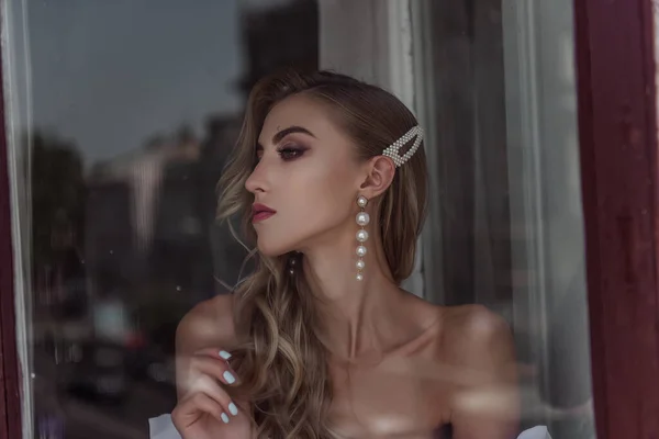 Gelinin Moda pozunun büyüleyici güzelliği pencerede. Pencereden modern bir gelinin portresi.