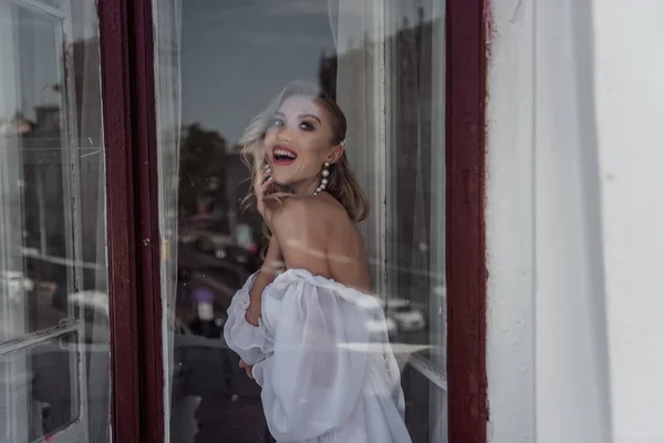 A charming beauty of the bride\'s Fashion pose at the window. Portrait of a modern bride through the window