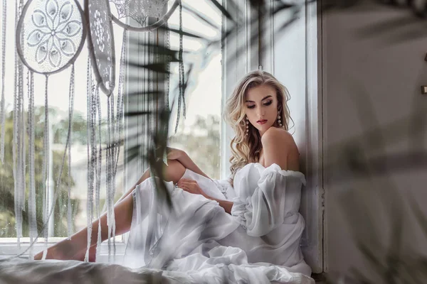 花嫁は新郎を待っている大きな窓にあります 白くて長いドレスを着たチャーミングな空気の花嫁 — ストック写真