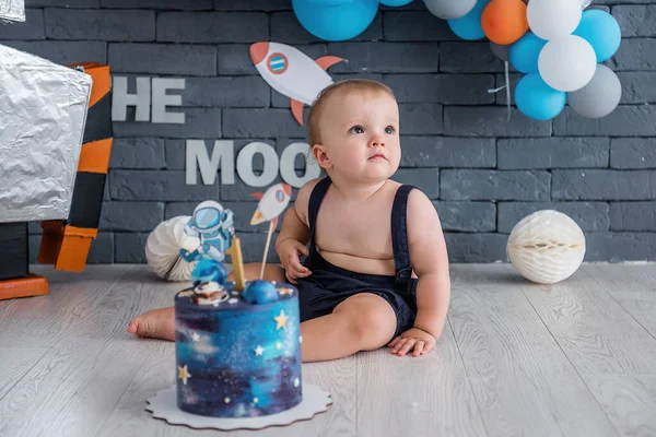 Küçük çocuk ilk doğum gününü kutluyor. Robot ve yıldızlı uzay tasarımı, bir sürü renkli balon.