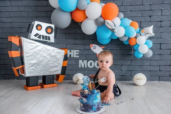Küçük çocuk ilk doğum gününü kutluyor. Robot ve yıldızlı uzay tasarımı, bir sürü renkli balon.