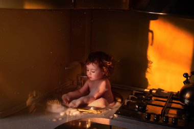 Küçük kız mutfaktaki lavaboda yıkanır. Bir salgın sırasında en önemli şey hijyendir. Mutfaktaki lavaboda köpük ve fırçayla yüzmek eğlencelidir..