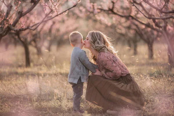 어머니가 걸어가다가 정원에서 아들을 껴안습니다 어머니는 아름다운 아들을 보호하고 맞추지요 — 스톡 사진