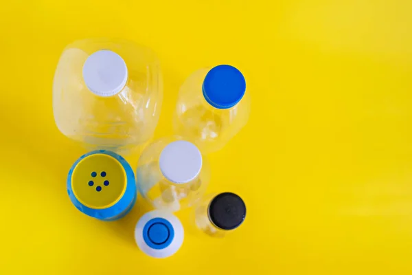 On a yellow background, plastic bottles from household chemicals stand isolated. It is necessary to sort the plastic and throw it into the containers intended for it. We will save our Earth