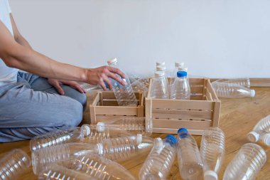 Plastik boş şişeyi tahta kutuya koyan kişi. Eko-plastiği ayırıyorum. Plastiksiz bir hayat. Çöpleri ayıklıyorum. Atık geri dönüşümü.