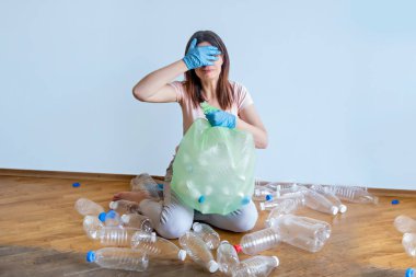 Kız boş plastik şişeleri bir torbaya koyar. Sıralama ve geri dönüşüm toprağın doğasını koruyacak. Sıralama zor değil.