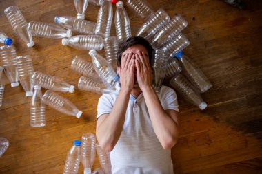 Çevresel plastik şişelerin arasında bir adam yatıyor. Biz ve etrafımızdaki plastik dünyamız. Gezegeni temiz tut, çöpü ve plastiği ayır ve geri dönüştür..