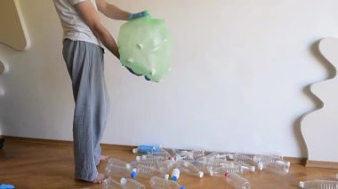 Adam plastik şişeleri toplayıp büyük plastik bir torbaya koyuyor. Ev temizliği pijamayla tüm kurallara göre yapılır..