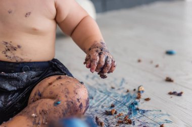 Güzel bir çocuk ilk pastasını mahveder, ayaklarını yalar ve mavi krem içinde yuvarlanır - bebek hayatının ilk doğum günü, Seçici ve Arka Ön Odaklanma