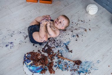 Küçük çocuk hayatındaki ilk doğum gününü kutluyor. Çocuk yer ve doğum günü pastasını sıçratır. Vızıltı. Güzel tatil..