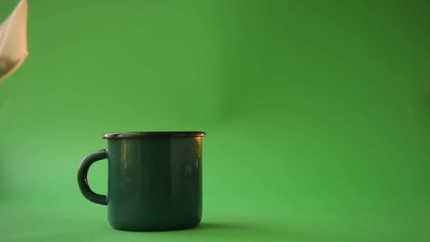 お茶作り ロープの上に綿100 のティーバッグが画面に表示され 緑の背景にお湯で緑のマグカップの上にスイングし 蒸気はマグカップから来ています 自然派のティーパックの概念は — ストック動画