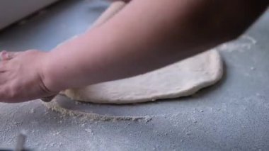 Hamurun pişirme, donma, heykel ve diğer yiyecek boşluklarına hazırlanması - masanın üzerinde büyük bir parça hamur var ve şef üzerinde demir bir şekille küçük daireler kesiyor. Kalıplama