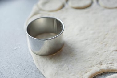 Hamurun pişirme, donma, heykel ve diğer yiyecek boşluklarına hazırlanması - masanın üzerinde büyük bir parça hamur var ve şef üzerinde demir bir şekille küçük daireler kesiyor. Kalıplama