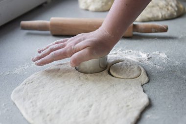 Hamurun pişirme, donma, heykel ve diğer yiyecek boşluklarına hazırlanması - masanın üzerinde büyük bir parça hamur var ve şef üzerinde demir bir şekille küçük daireler kesiyor. Kalıplama