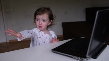 Çekici küçük bir kız dizüstü bilgisayarın arkasında oturur ve uzaktan izler ve modern erken gelişim konsepti olan erken gelişim derslerine katılır. Küçük bir kız dizüstü bilgisayarda başka bir video izlemek istiyor.