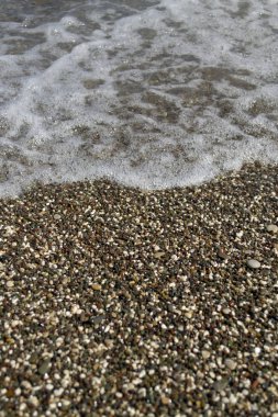 Deniz kıyısında çakıl taşları. Denize yakın el salla
