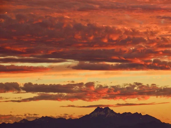 Seattle, Washington yakınlarındaki Olimpiyat Dağları 'ndaki Kardeşler Tepeleri' nin üzerinde turuncu, bulutlarla dolu gün batımı.