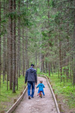 Baba ve oğul ormanda yürürler. Bebekli adam yola koyul..
