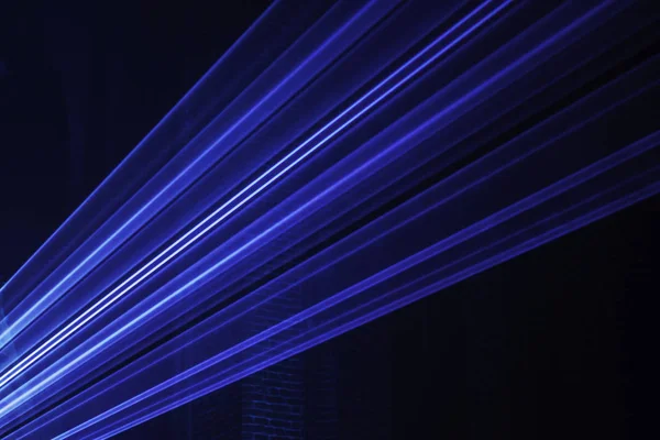 Abstract background with blurred ray of light. Lighting and spotlights lines, stage light and smoke. Disco laser with beams through smoke. Classic blue, trend color. Color of the year